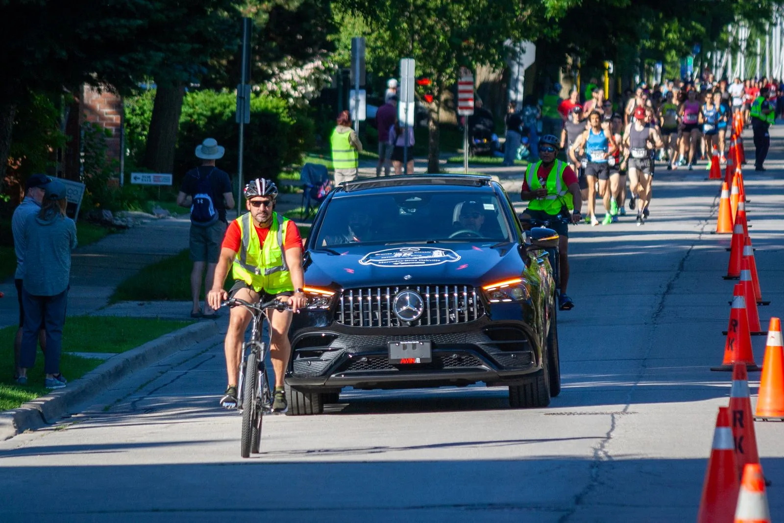The Mercedes-Benz Oakville pace car and lead cyclist escorts guiding the packed lead group of runners along the Bronte Harbour Classic 5K course, Oakville, Ontario