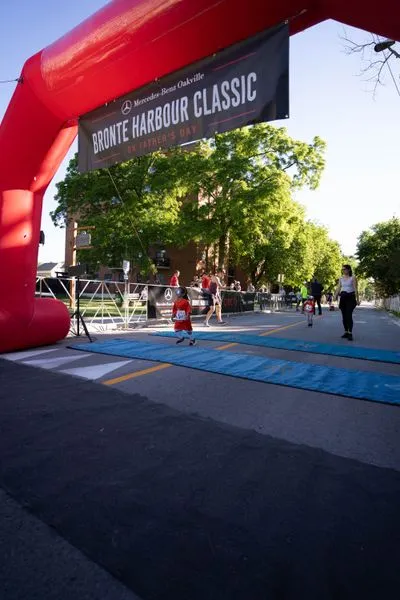 Bronte Harbour Classic 5K 2026 official race photo: Kids 1K, Bib 1, Mercedes-Benz Oakville, CIBC, Be Active Physio, Fortinos, Festival.