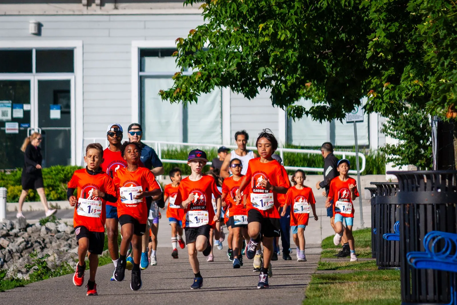 Children in orange race shirts running the Speak Squad Kids 1K Fun Run at the 2026 Bronte Harbour Classic, Bronte Heritage Waterfront Park, Oakville