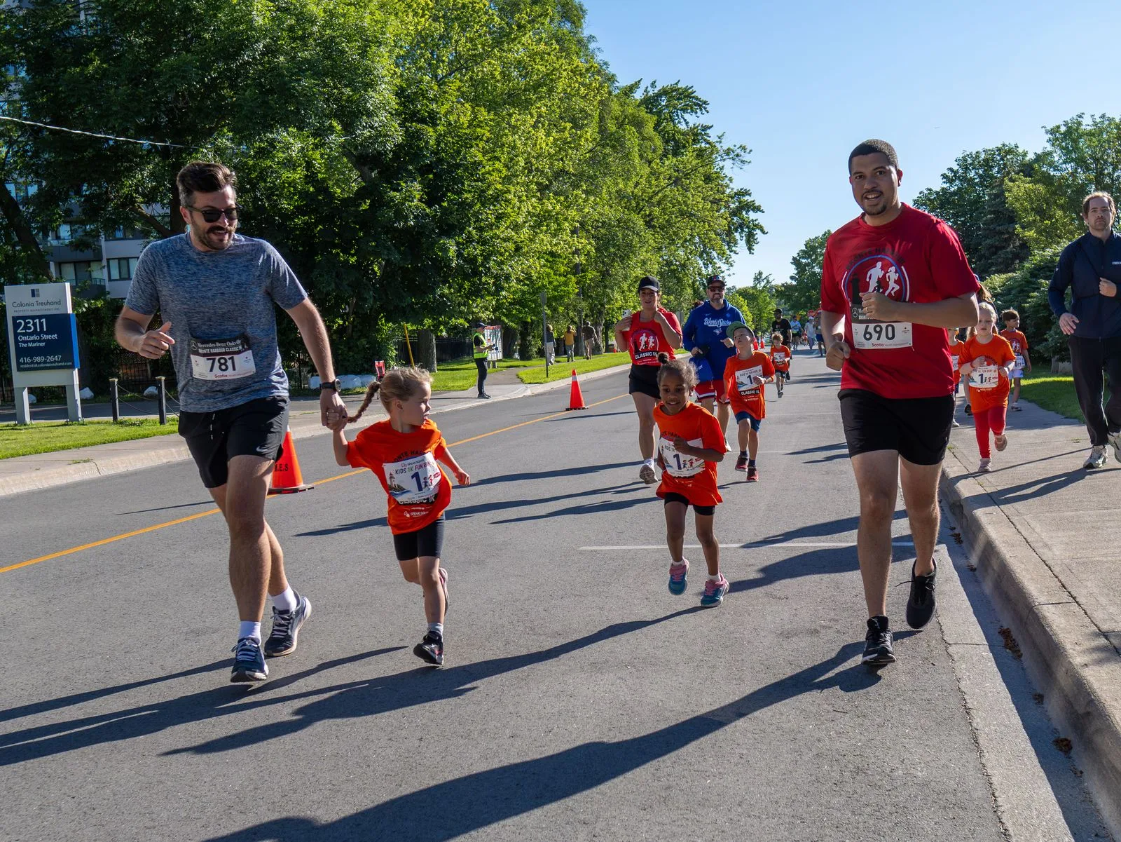 A father running the Mercedes-Benz Oakville Bronte Harbour Classic course in Oakville hand-in-hand with his children